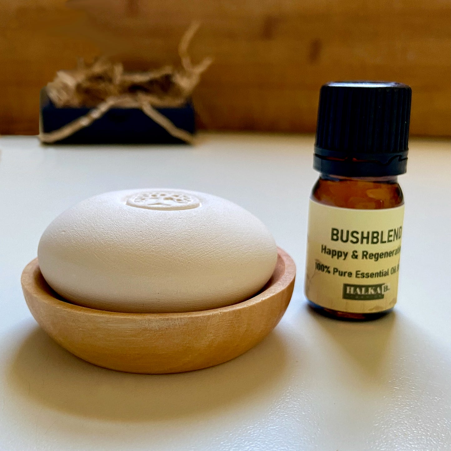 Scent Pebble resting in a wooden dish beside a small amber bottle of essential oil, showcasing a minimalist and natural aromatherapy setup.