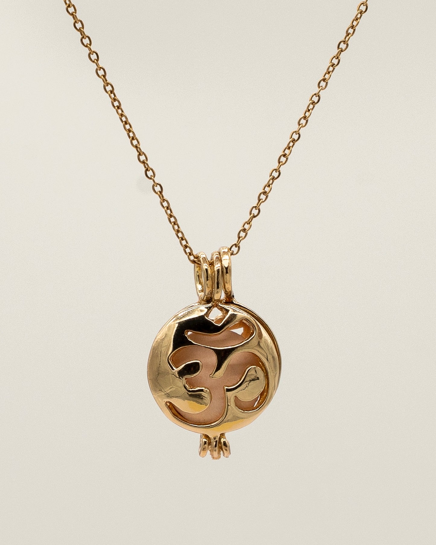 Gold Scent Locket necklace with a delicate chain and a round pendant featuring an intricate cut-out design, ideal for holding aromatherapy scents close.