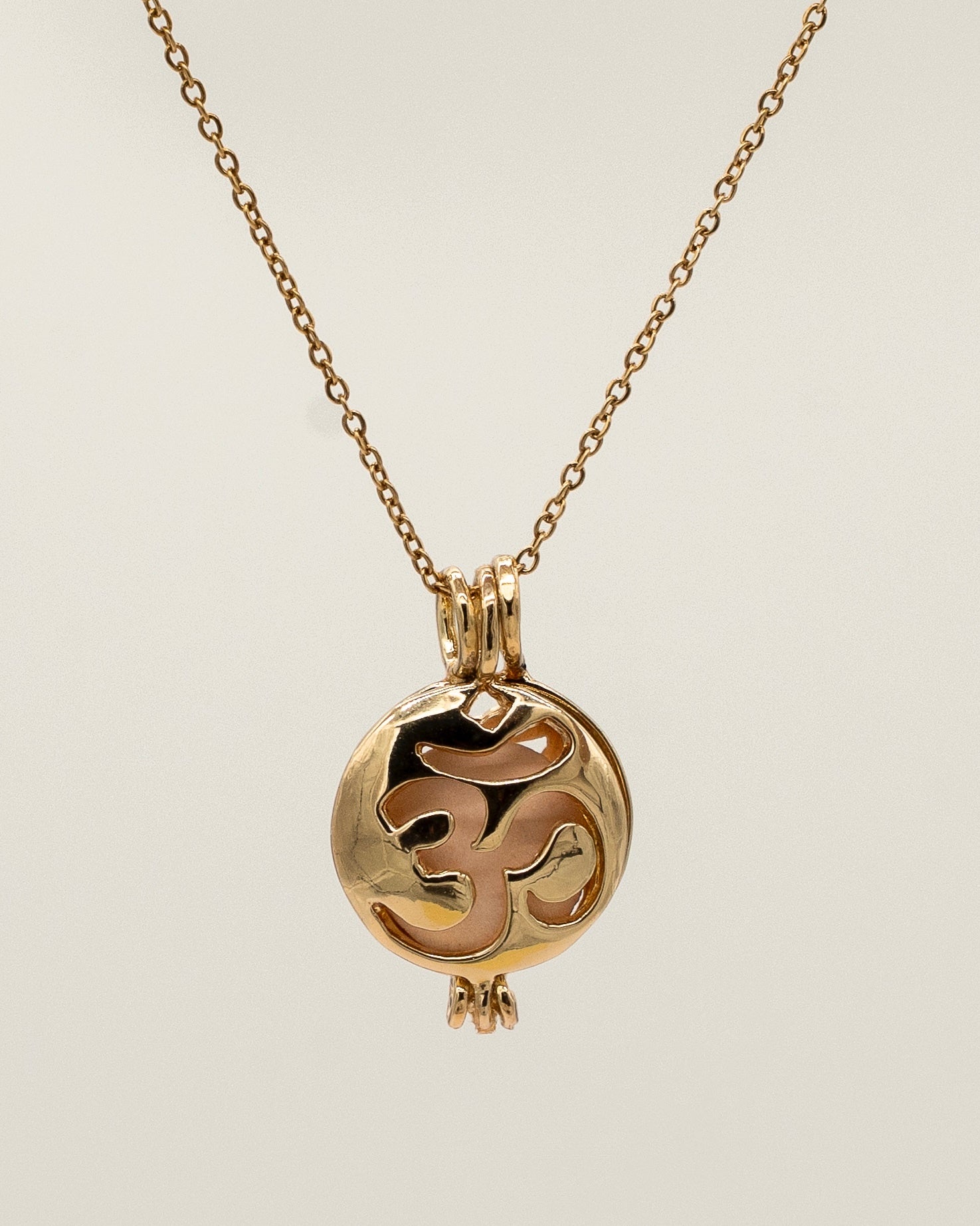 Gold Scent Locket necklace with a delicate chain and a round pendant featuring an intricate cut-out design, ideal for holding aromatherapy scents close.