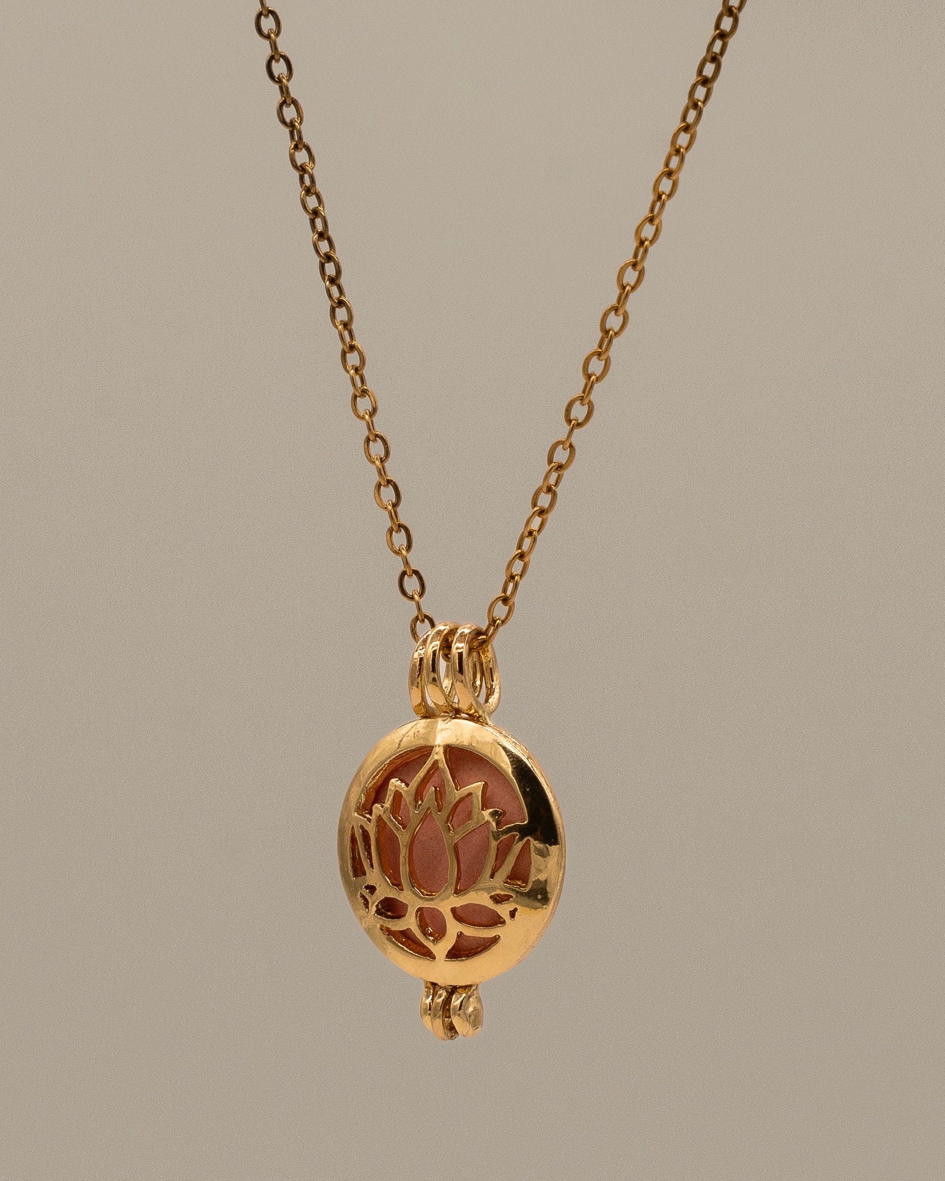 Gold Scent Locket hanging from a delicate chain, featuring a lotus flower design with an inner compartment for aromatherapy use.