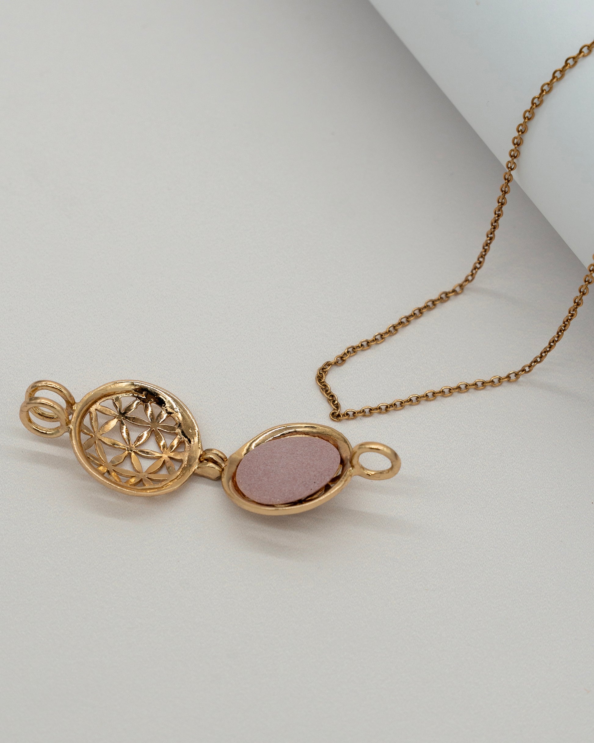 Gold Scent Locket open to reveal a decorative interior designed for aromatherapy, hanging from a delicate gold chain on a light surface.