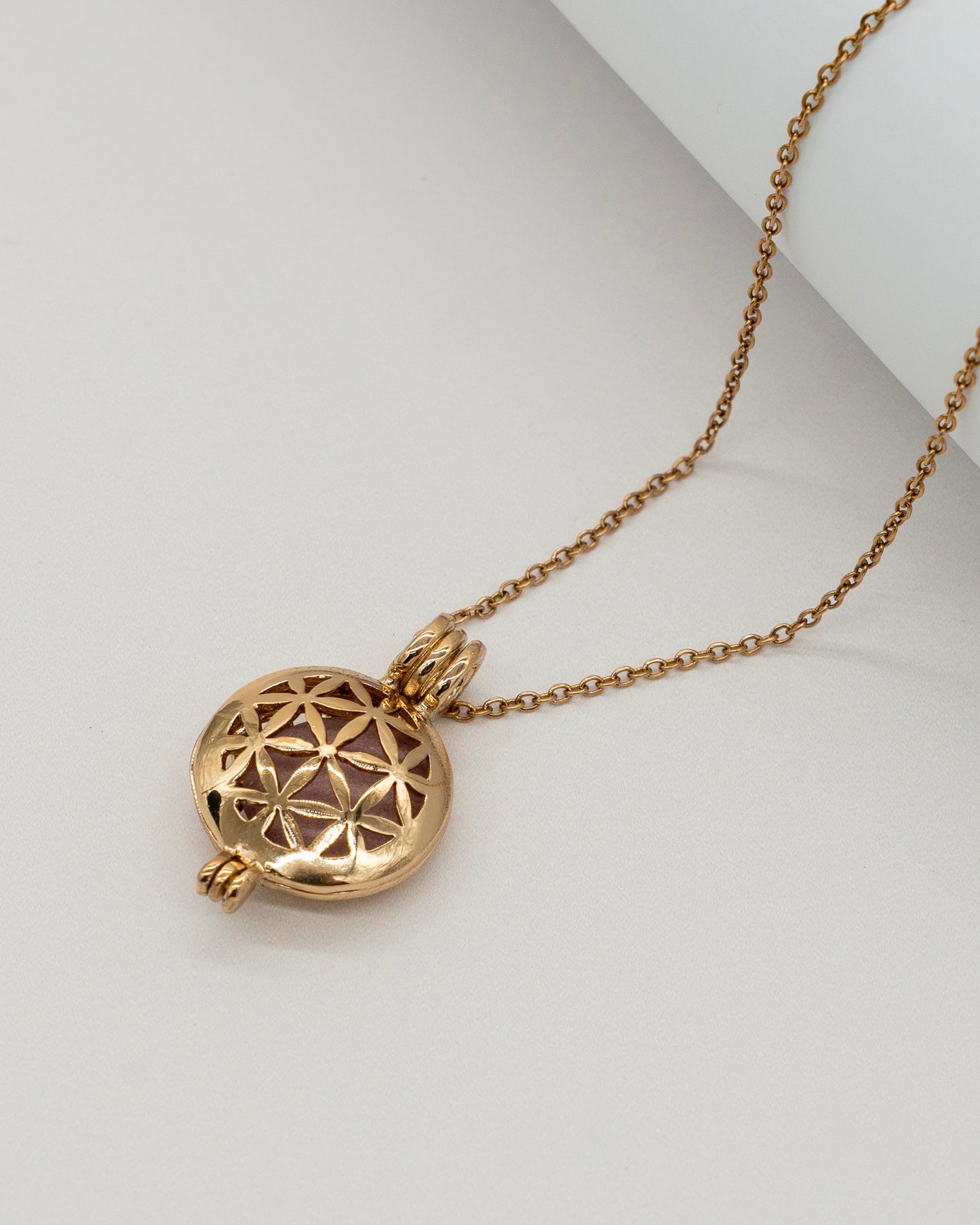 Gold Scent Locket featuring an intricate floral pattern on a smooth round pendant, suspended from a delicate gold chain, designed for wearable aromatherapy.