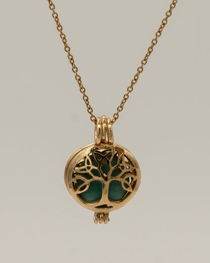 Gold Scent Locket featuring an intricate tree of life design in gold with a green aromatherapy insert, hanging from a delicate gold chain necklace.