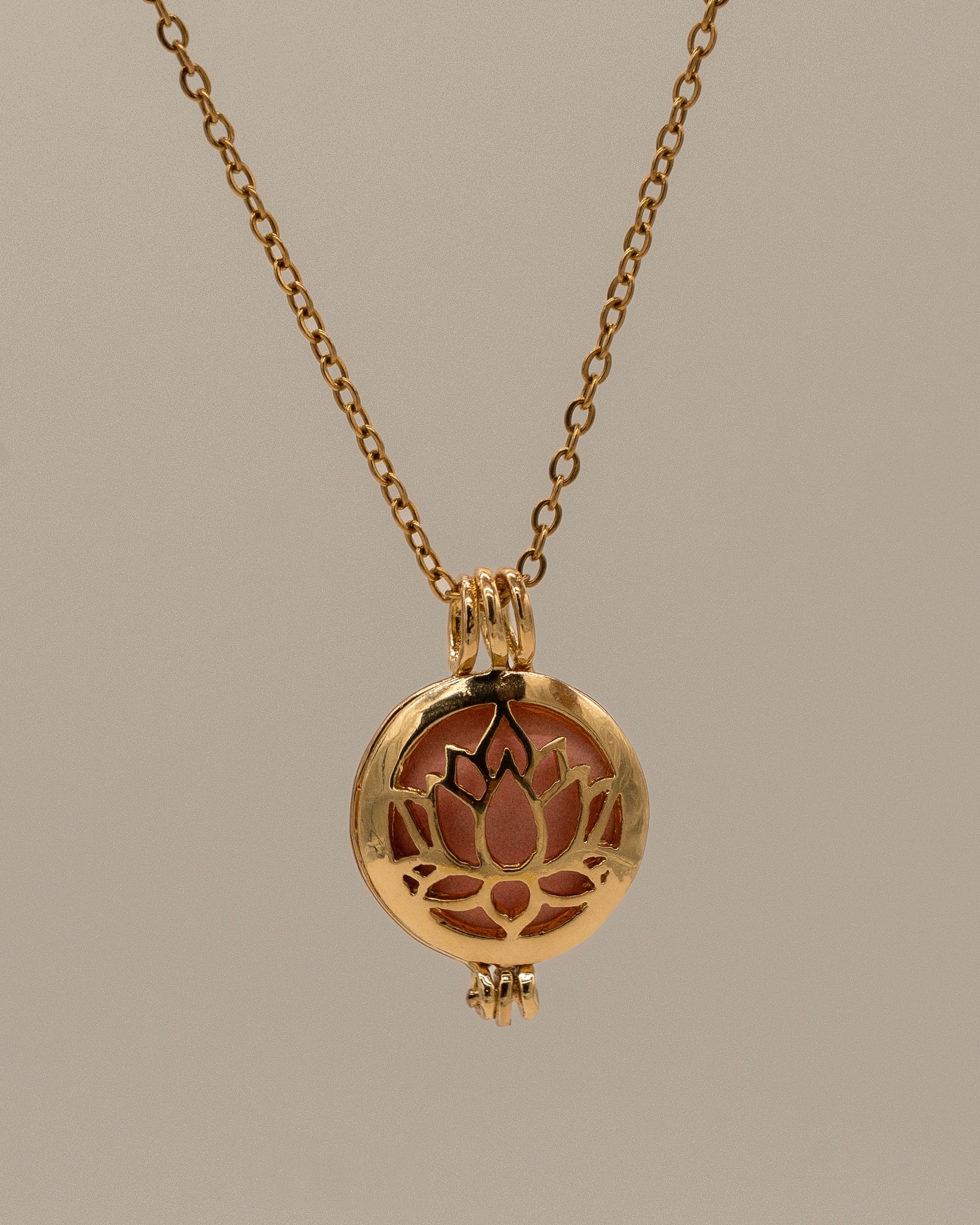Gold Scent Locket featuring a delicate gold chain and a round pendant with a lotus flower cutout design, designed for aromatherapy use.
