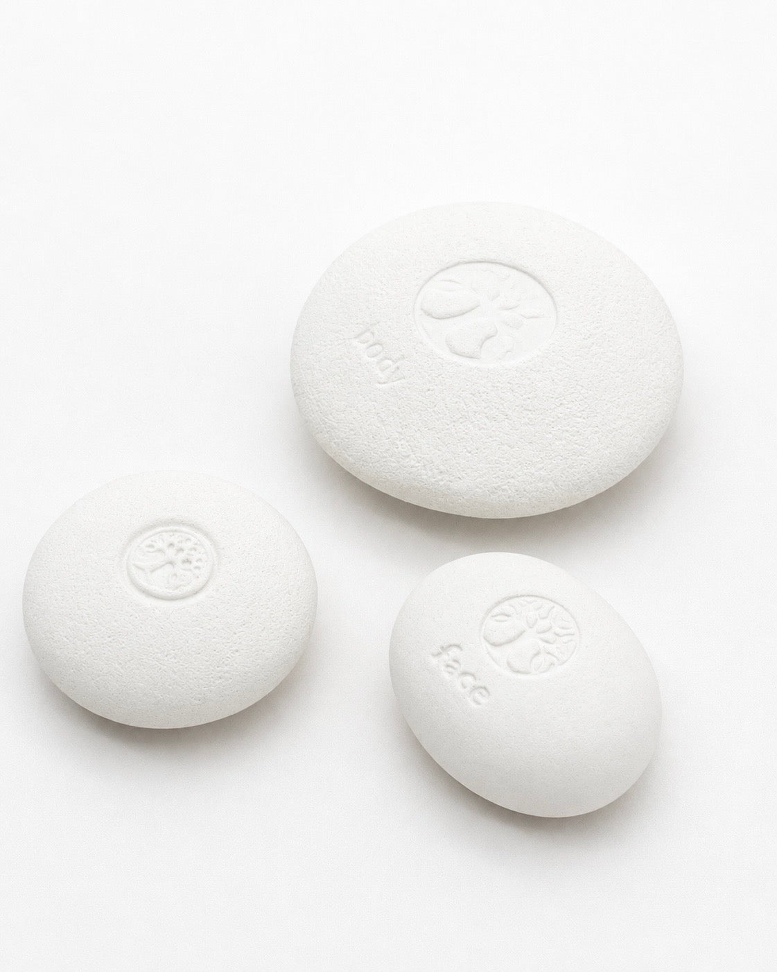 Set of three white Body Pebble stones designed for myofascial massage and exfoliation, featuring smooth rounded shapes with subtle embossed icons.