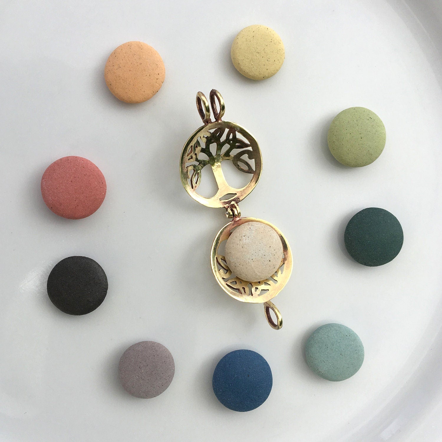 Gold tree-shaped pendant with a beige sphere on a white background with colorful round stones.