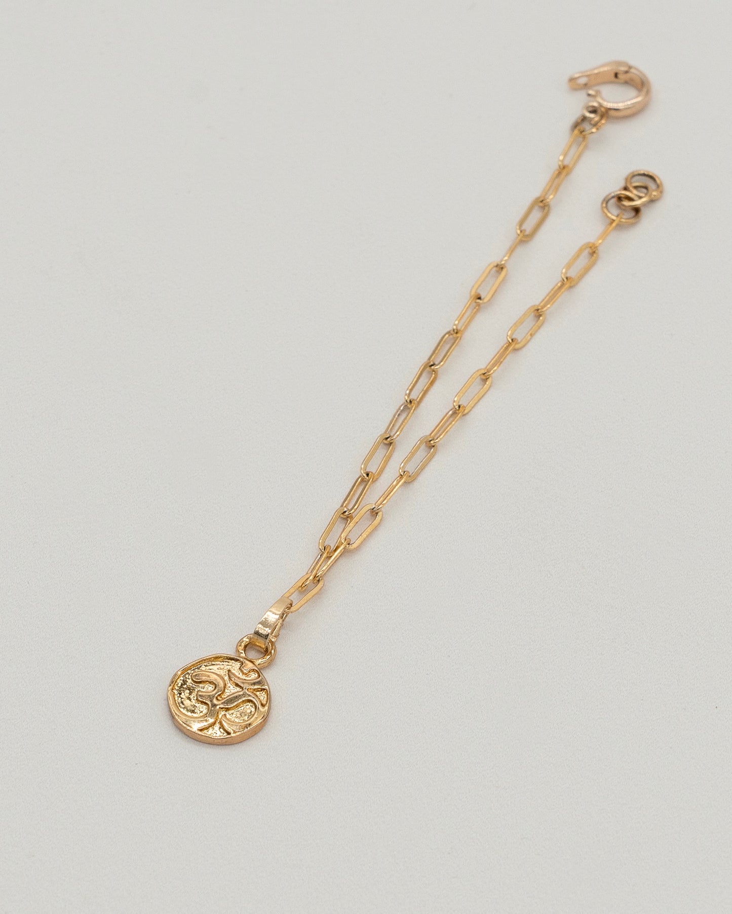 Gold-tone Charm Bracelet with a delicate chain link design and a round engraved pendant, elegant and versatile for everyday wear or special occasions.