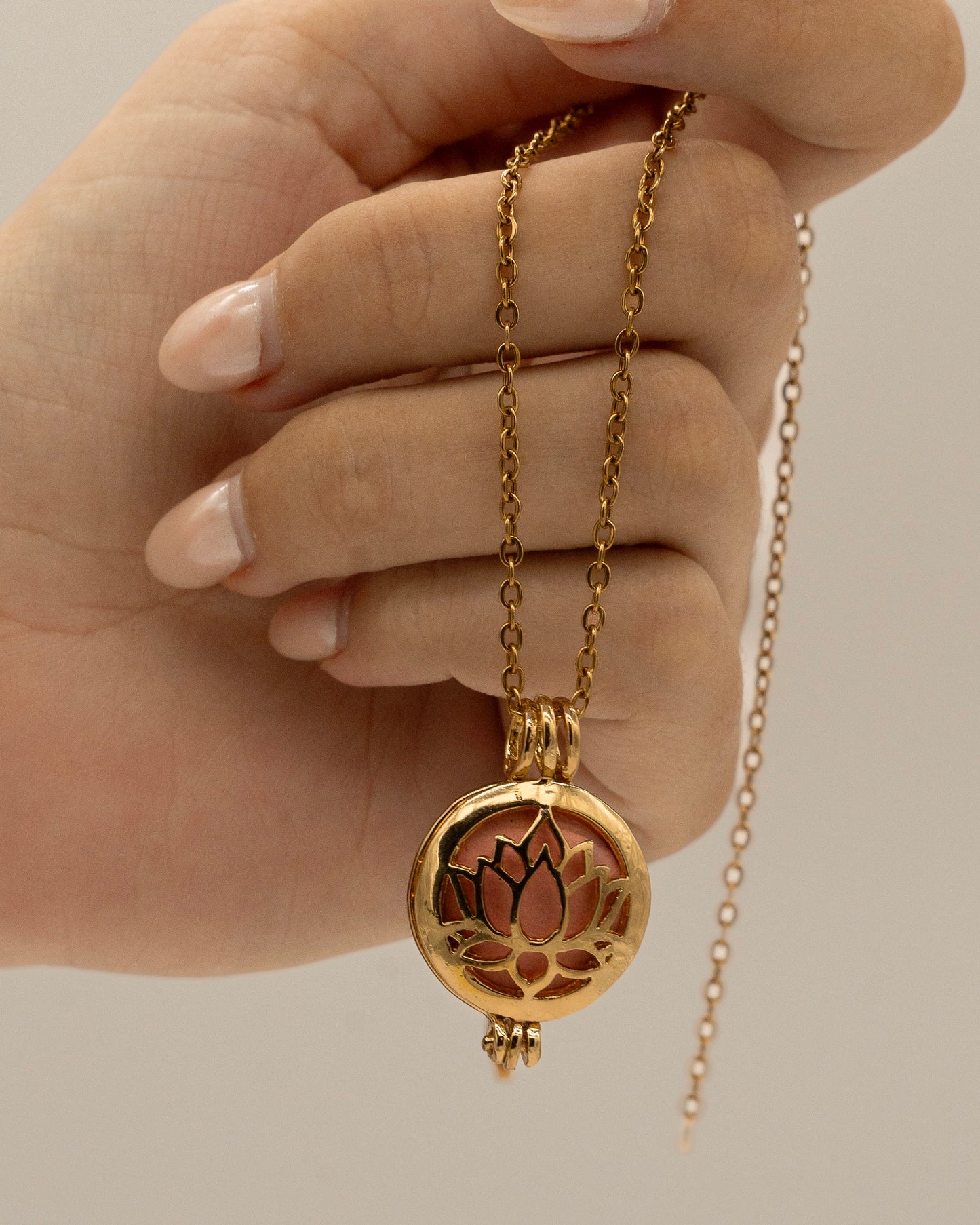 Hand holding a delicate Gold Scent Locket with a lotus flower design on a fine chain, designed for aromatherapy use.