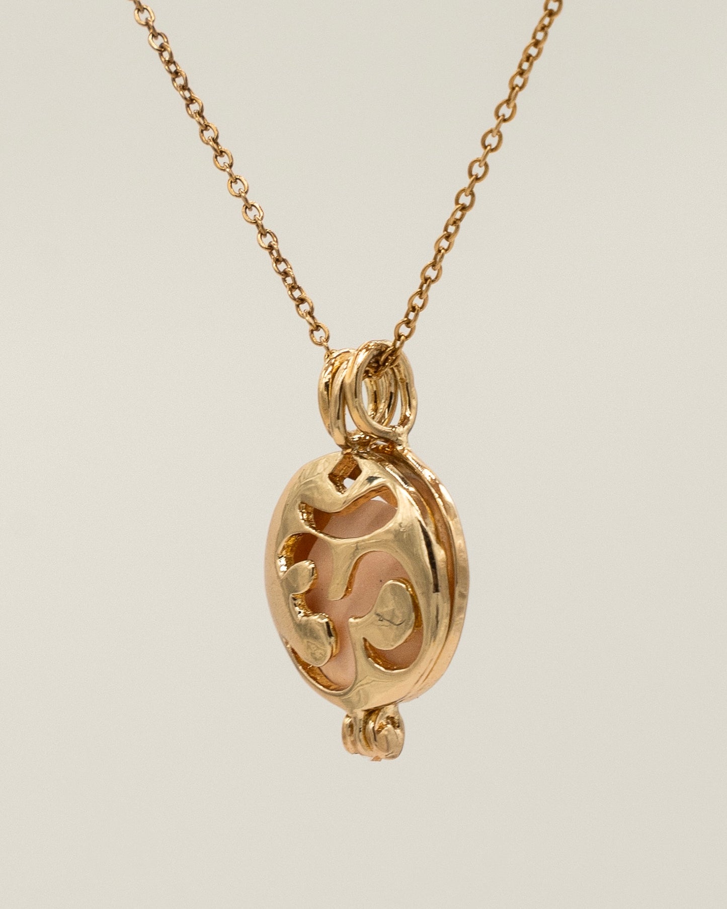Close-up of a delicate Gold Scent Locket necklace featuring an intricate openwork design on a fine chain, perfect for aromatherapy use.