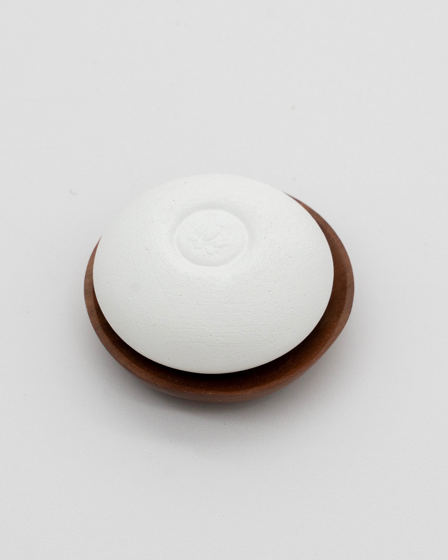 White Scent Pebble resting on a small wooden dish, designed for gentle aromatherapy and eco-friendly relaxation.
