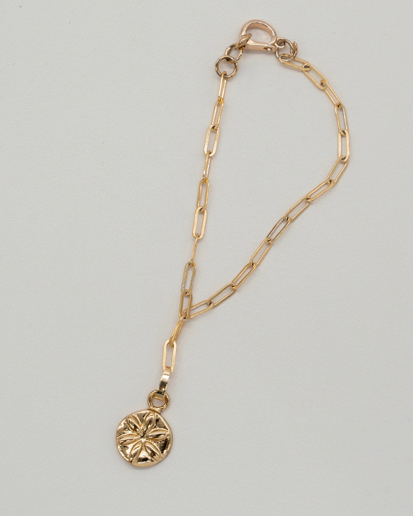 Delicate gold chain with elongated links featuring a round floral pendant, styled as a Charm Bracelet with a secure lobster clasp closure.