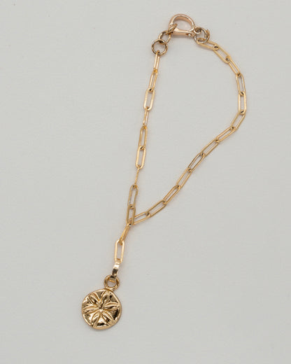 Delicate gold chain with elongated links featuring a round floral pendant, styled as a Charm Bracelet with a secure lobster clasp closure.