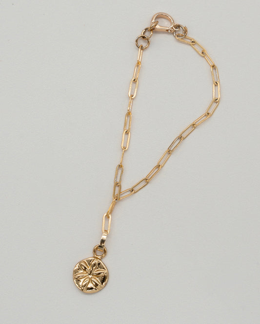 Delicate gold chain with elongated links featuring a round floral pendant, styled as a Charm Bracelet with a secure lobster clasp closure.