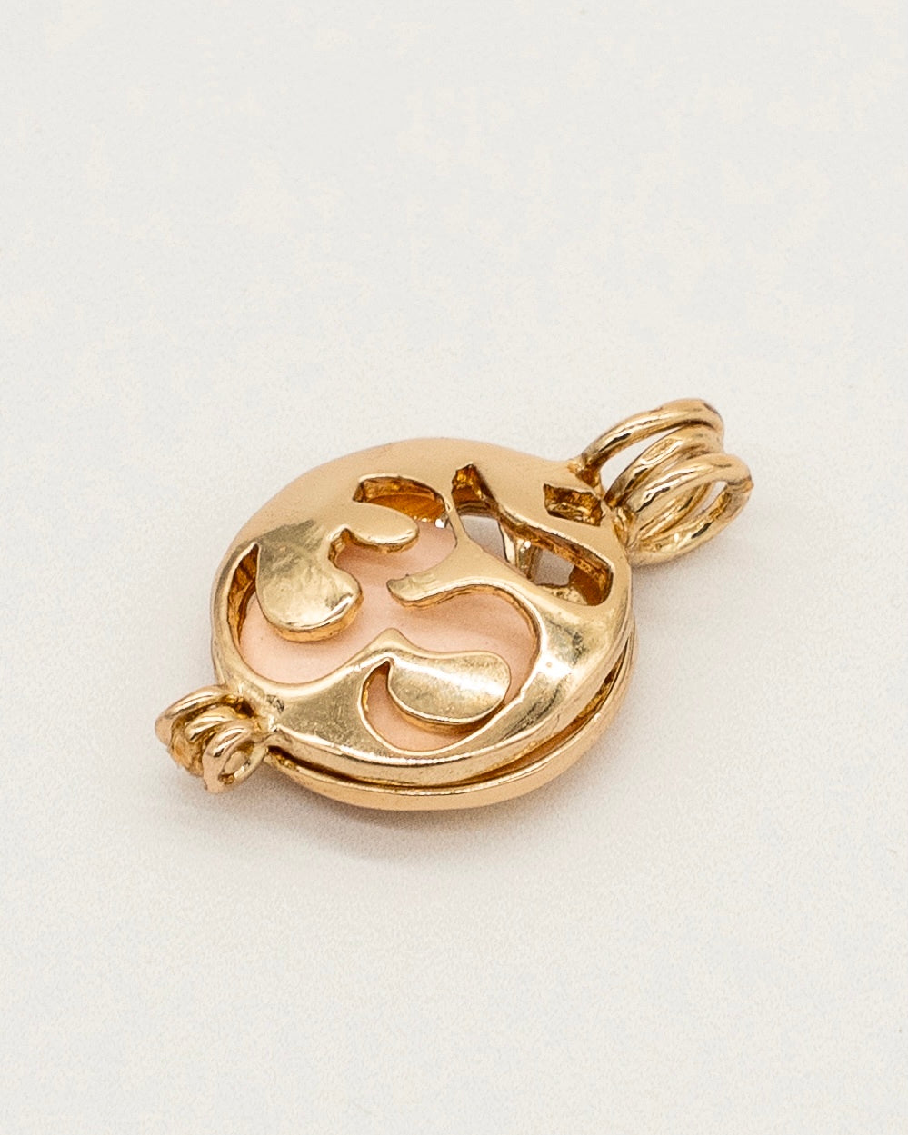Gold Scent Locket in polished gold finish with intricate cut-out design, featuring a soft pink insert for holding fragrance, perfect for aromatherapy use.