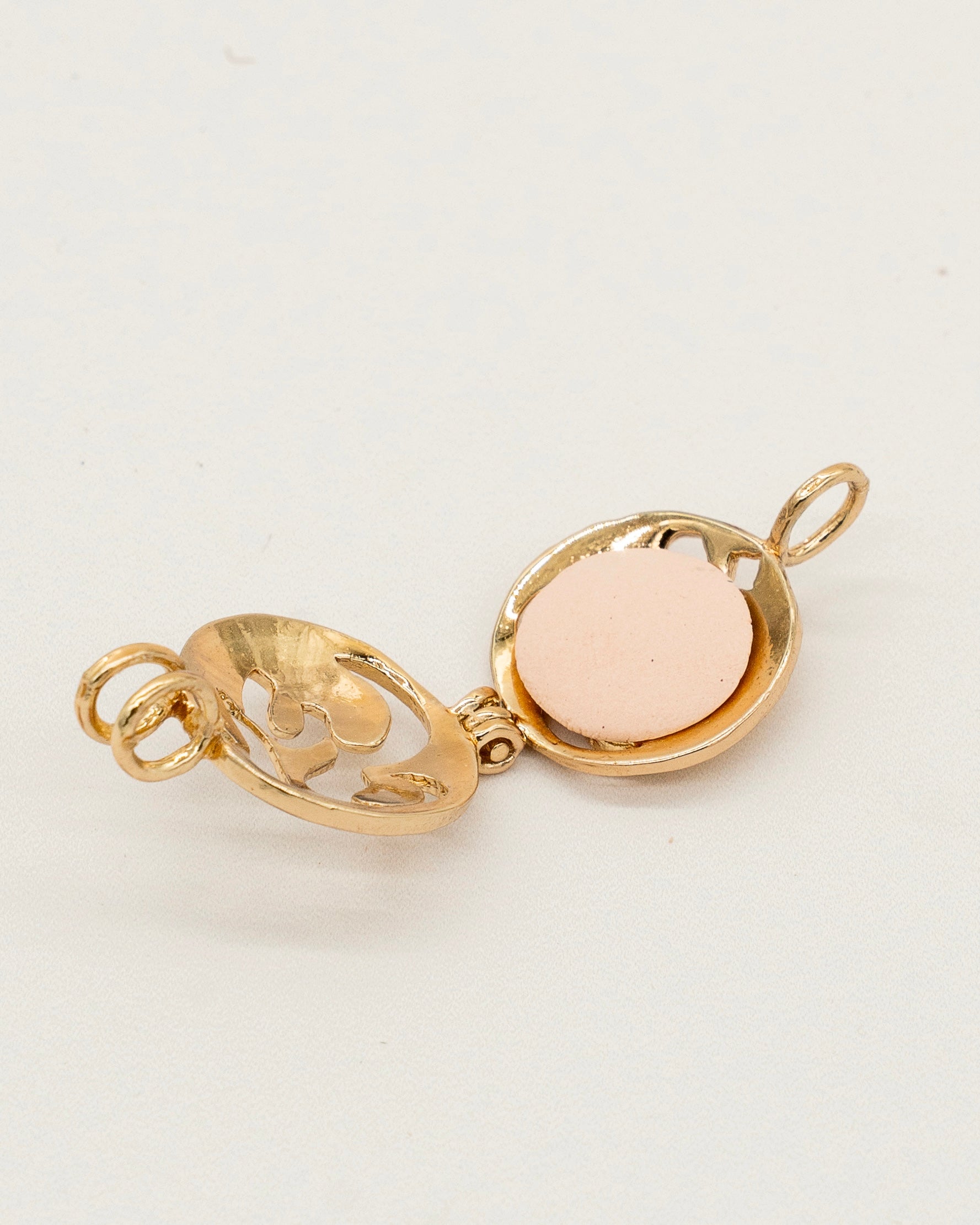 Gold Scent Locket open to show a round aromatic pad inside, stylish gold-tone metal with delicate cutout floral design for aromatherapy use.