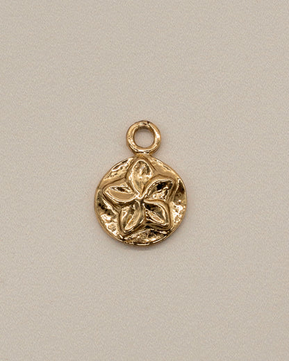 Close-up of a small gold charm with a floral design, designed as a decorative element for the Charm Bracelet.