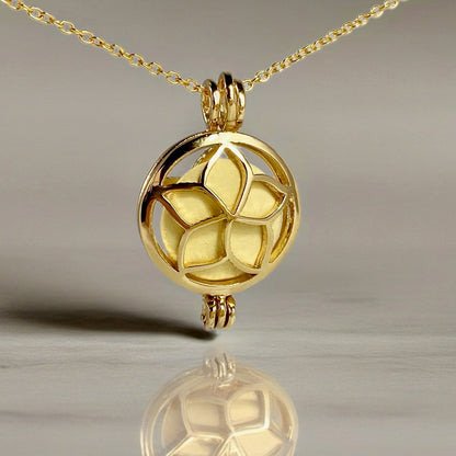 gold locket in a chain with a frangipani flower design and a yellow stone inside