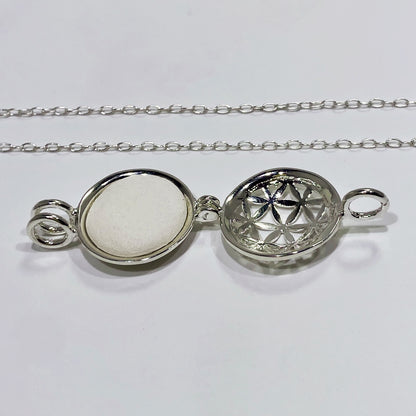 silver locket open with a white stone inside and a chain in a white background