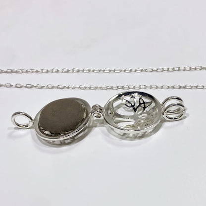 silver locket open with a black stone inside and a chain in a white background
