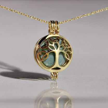 gold locket in a chain with a tree design and a green stone inside